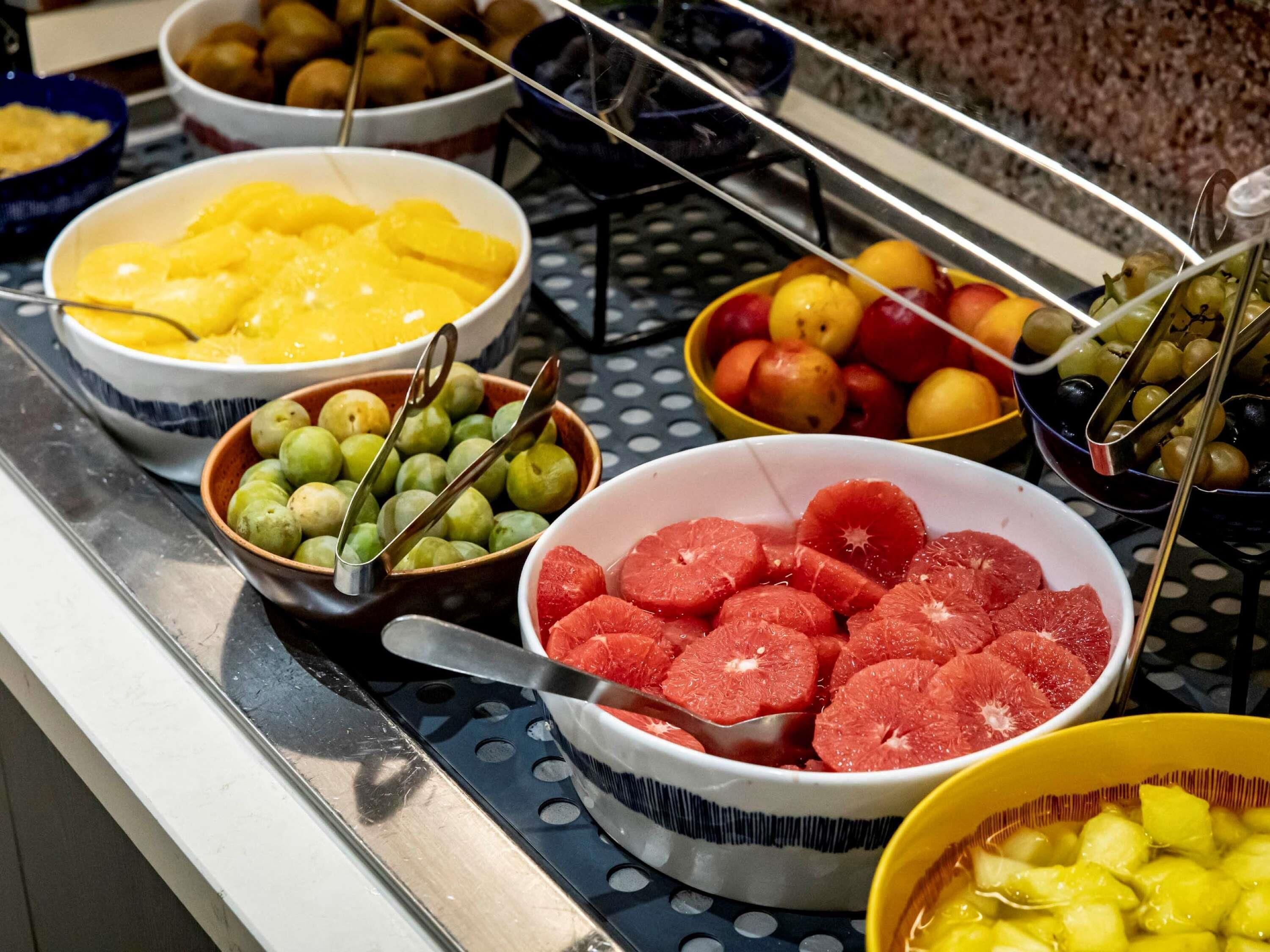 A buffet with various fruits including pineapple, grapes, and oranges.