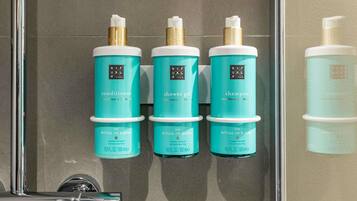 Three bottles of The Ritual of Karma conditioner, shower gel, and shampoo in a bathroom.