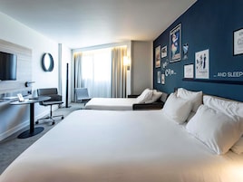 Una habitación de hotel con una cama grande, un escritorio, una silla y un televisor.