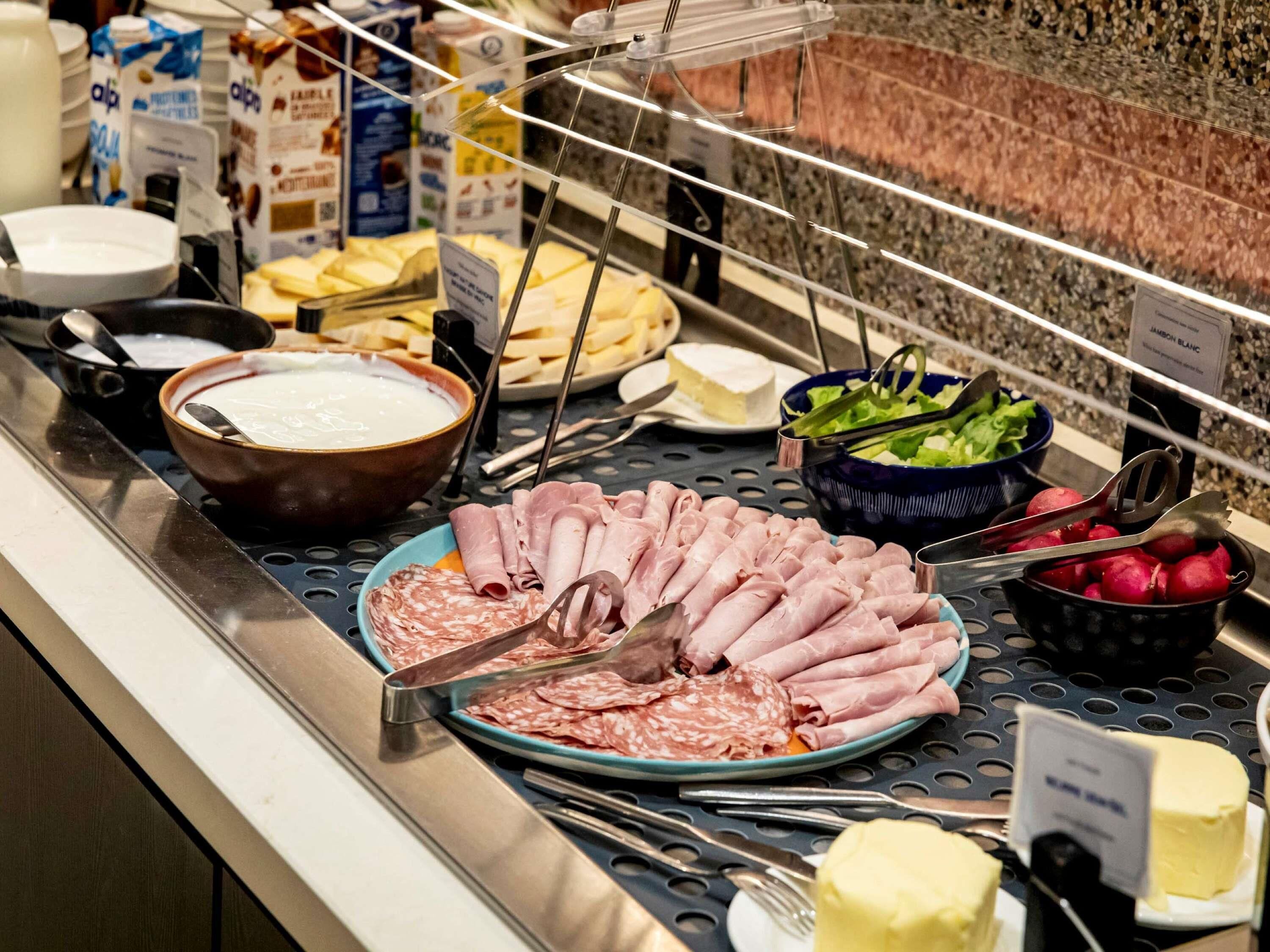 A buffet with various food items including meats, cheeses, and salads.