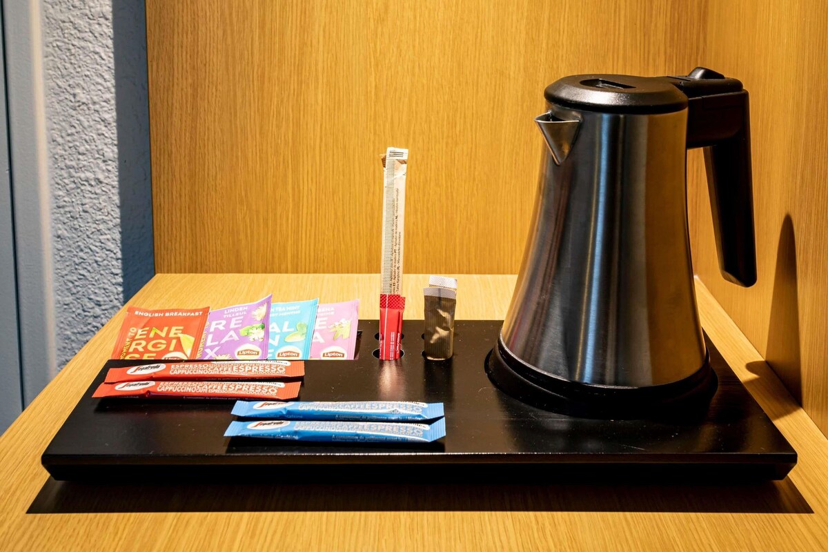 A coffee maker, a red and white striped pen, and several packets of Lipton tea on a black tray.