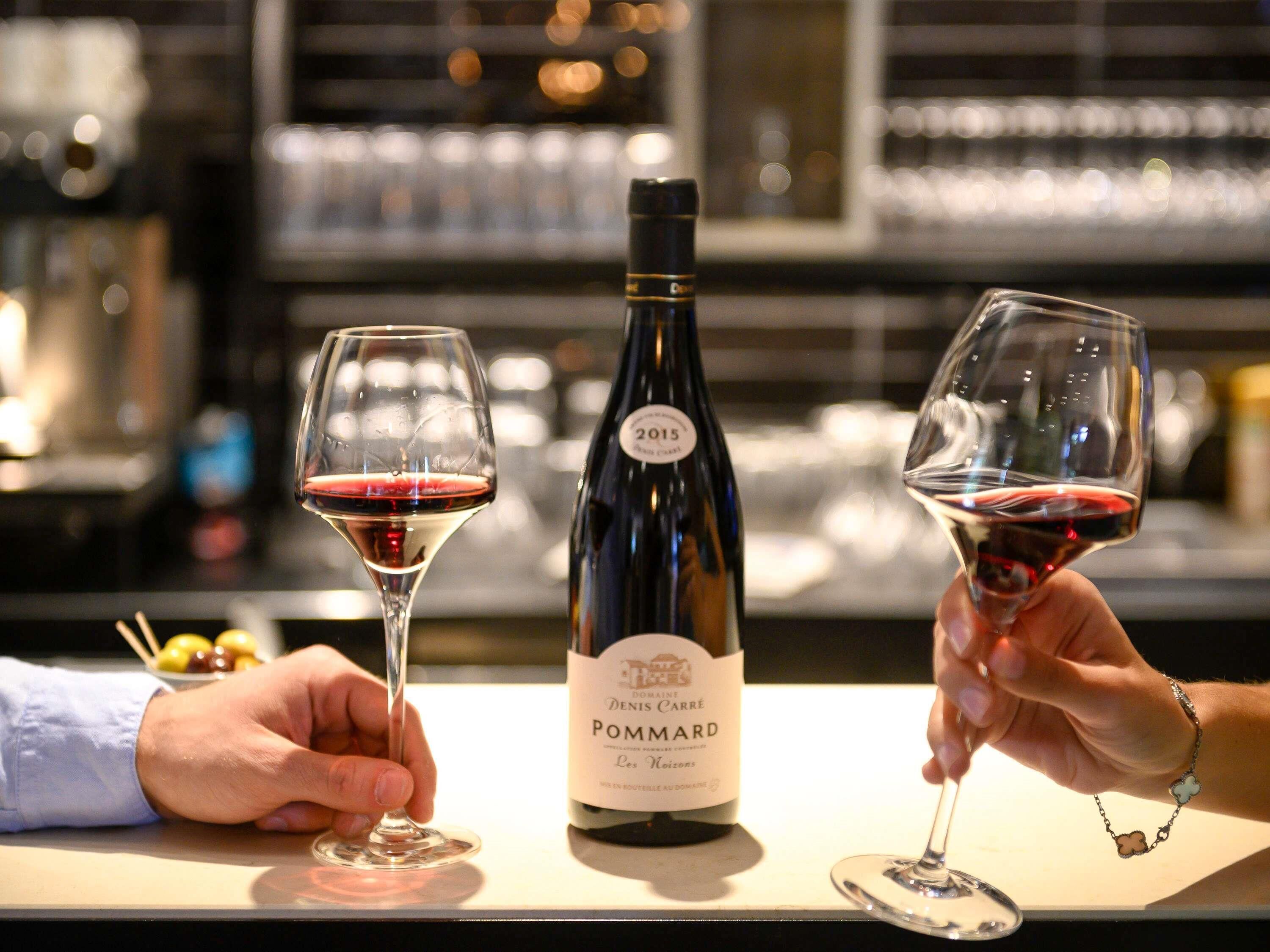 A bottle of Pommard wine with two wine glasses filled with red wine.
