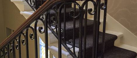 A staircase with a wooden handrail and black metal balusters.