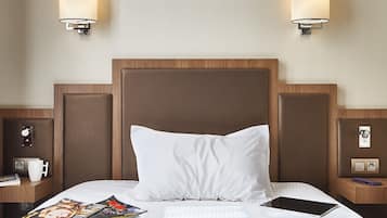 Habitación de hotel con una cama grande, dos mesitas de noche, una silla roja y lámparas de pared.
