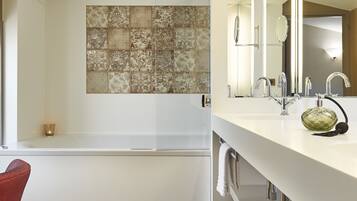 Une salle de bain moderne avec une baignoire, un grand miroir et un plancher en bois.