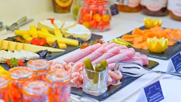 Una tabla de embutidos con varios quesos, carnes y pepinillos.