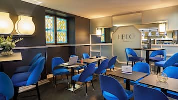 Una camera d'albergo moderna con sedie blu, un laptop e un cartello con su scritto "HBEO Bordeaux".