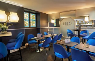 Una camera d'albergo moderna con sedie blu, un laptop e un cartello con su scritto "HBEO Bordeaux".