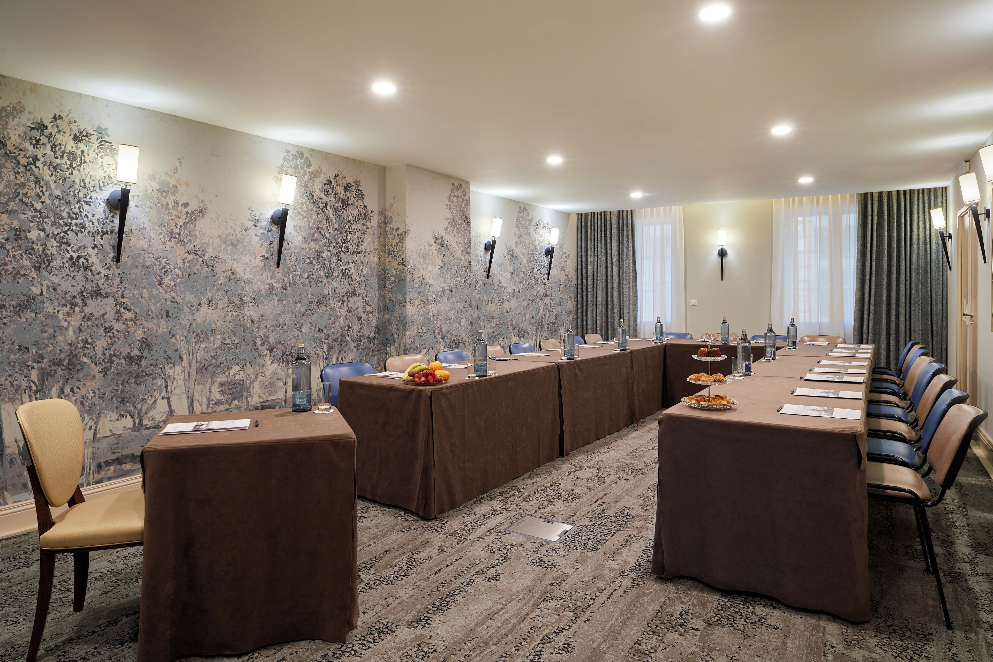 Un salón de conferencias con una mesa larga, sillas y una alfombra estampada.