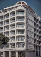 A modern hotel with multiple balconies, large windows, and a prominent sign reading "HOTEL BELLE PLAGE".