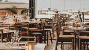A restaurant with tables set for dining, large windows, and a view of the sea. - Hôtel & Spa Belle Plage (Cannes)