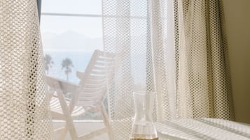 A balcony with a white railing, a wicker bottle, two clear glasses, and a wicker vase.