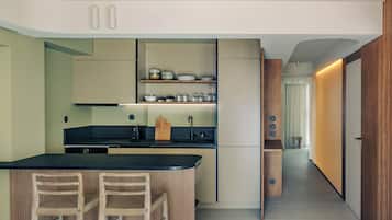 A modern kitchen with a central island, bar stools, and built-in shelves.