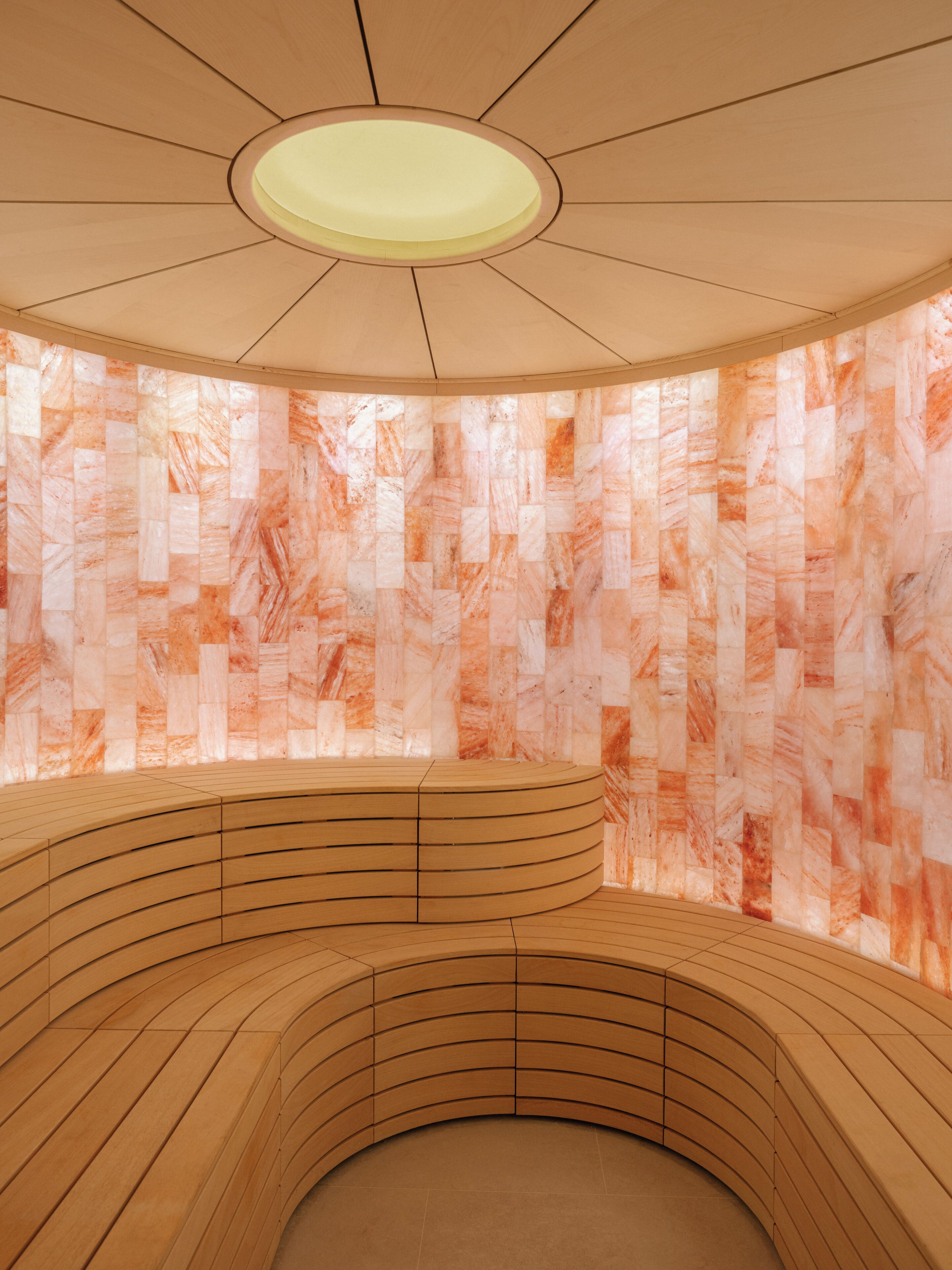 A circular wooden seating area with a patterned wall in the background.