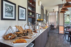 Een buffetgedeelte met diverse gerechten, ingelijste foto's aan de muur en een zithoek op de achtergrond.