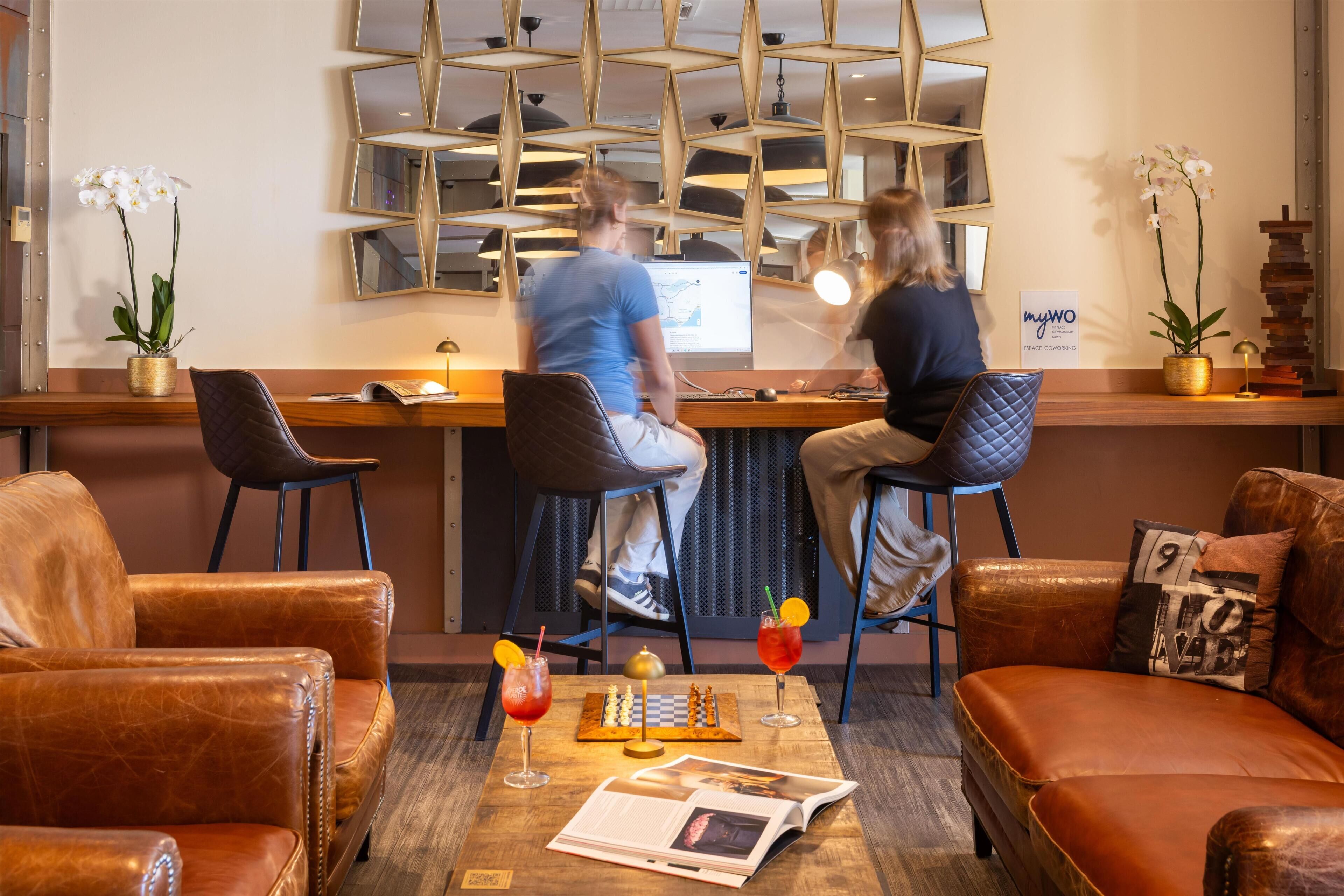 A modern bar area with leather seating, a chessboard, and two orchids.