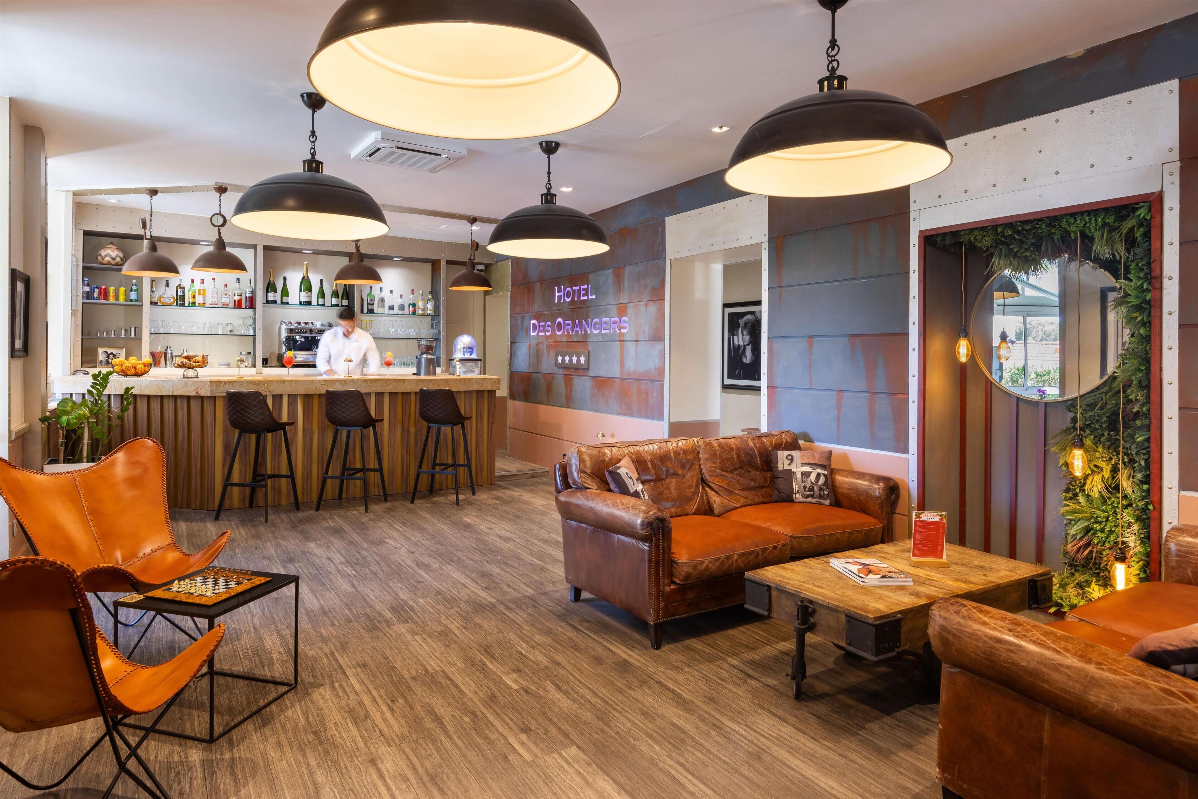 A hotel lobby with leather seating, a bar area, and a chef preparing food.