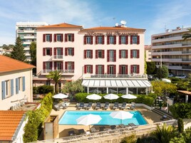Een hotel met een zwembad, terras en een overdekt gedeelte.