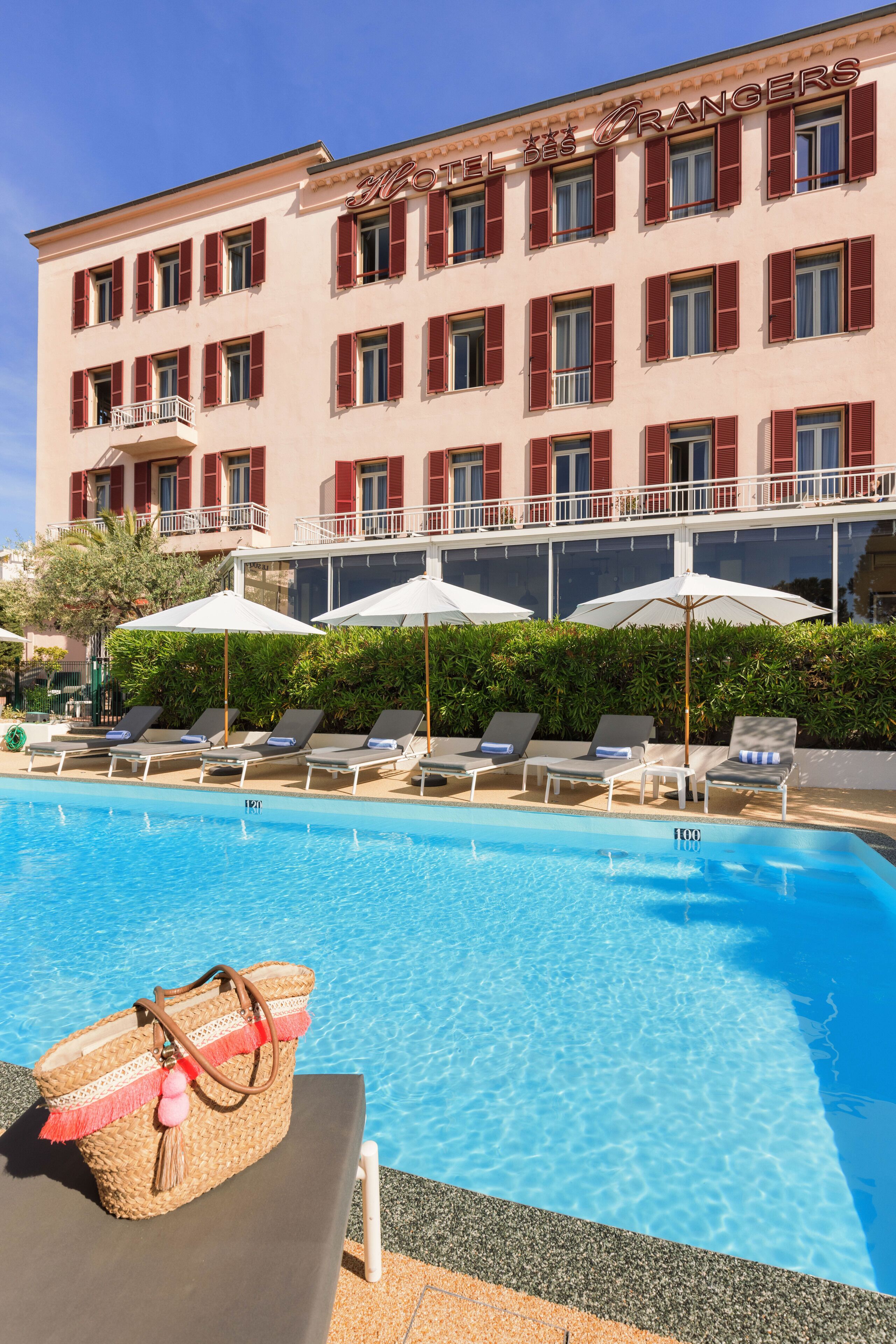 Un hotel con piscina, tumbonas y sombrillas.