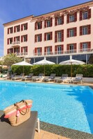 Un hotel con piscina, tumbonas y sombrillas.
