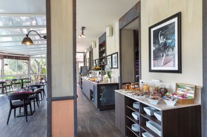 A modern restaurant with a long counter, dining area, and kitchen.