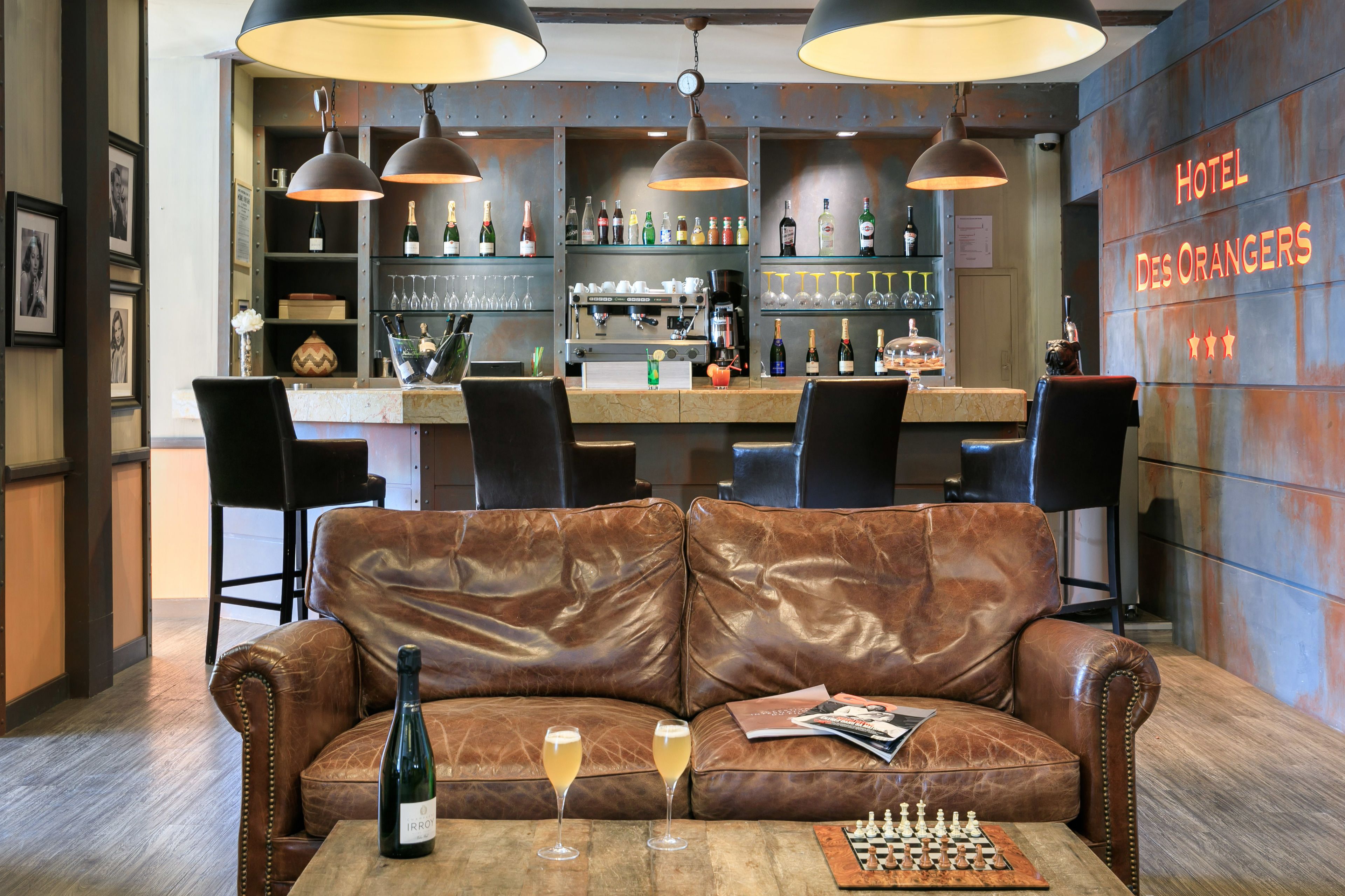 A bar area with leather seating, a chessboard, and a bottle of wine on a table.