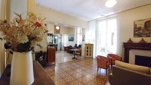 Un salon spacieux doté d’un parquet à motifs, d’une cheminée et d’un coin repas avec des chaises et une table.