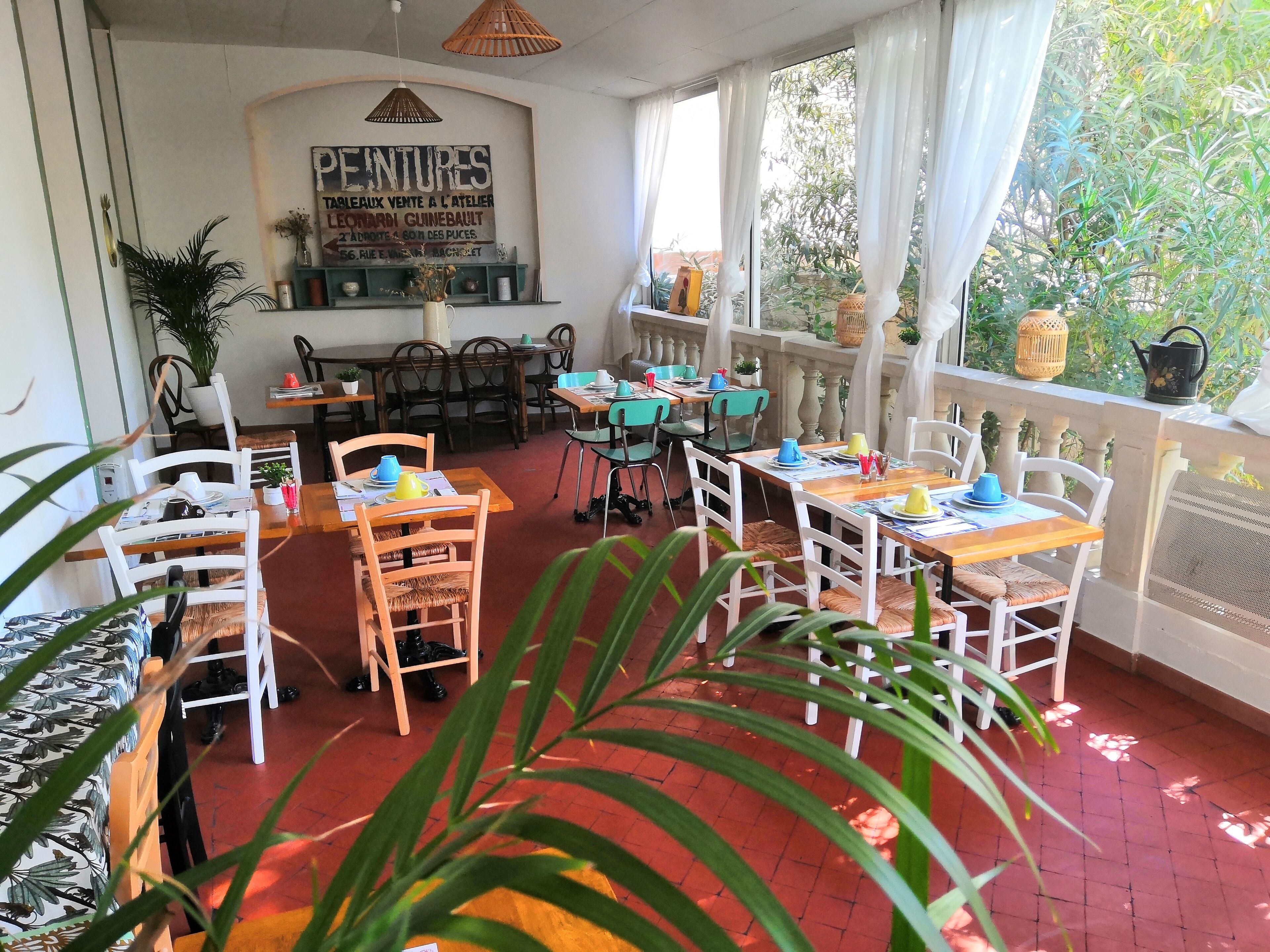 Un restaurante con mesas y sillas, un letrero en la pared y vistas a zonas verdes.