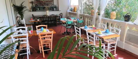 Un restaurante con mesas y sillas, un letrero en la pared y vistas a zonas verdes.