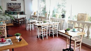 Un café avec des meubles blancs, un sol carrelé et une vue dégagée grâce à de grandes fenêtres.