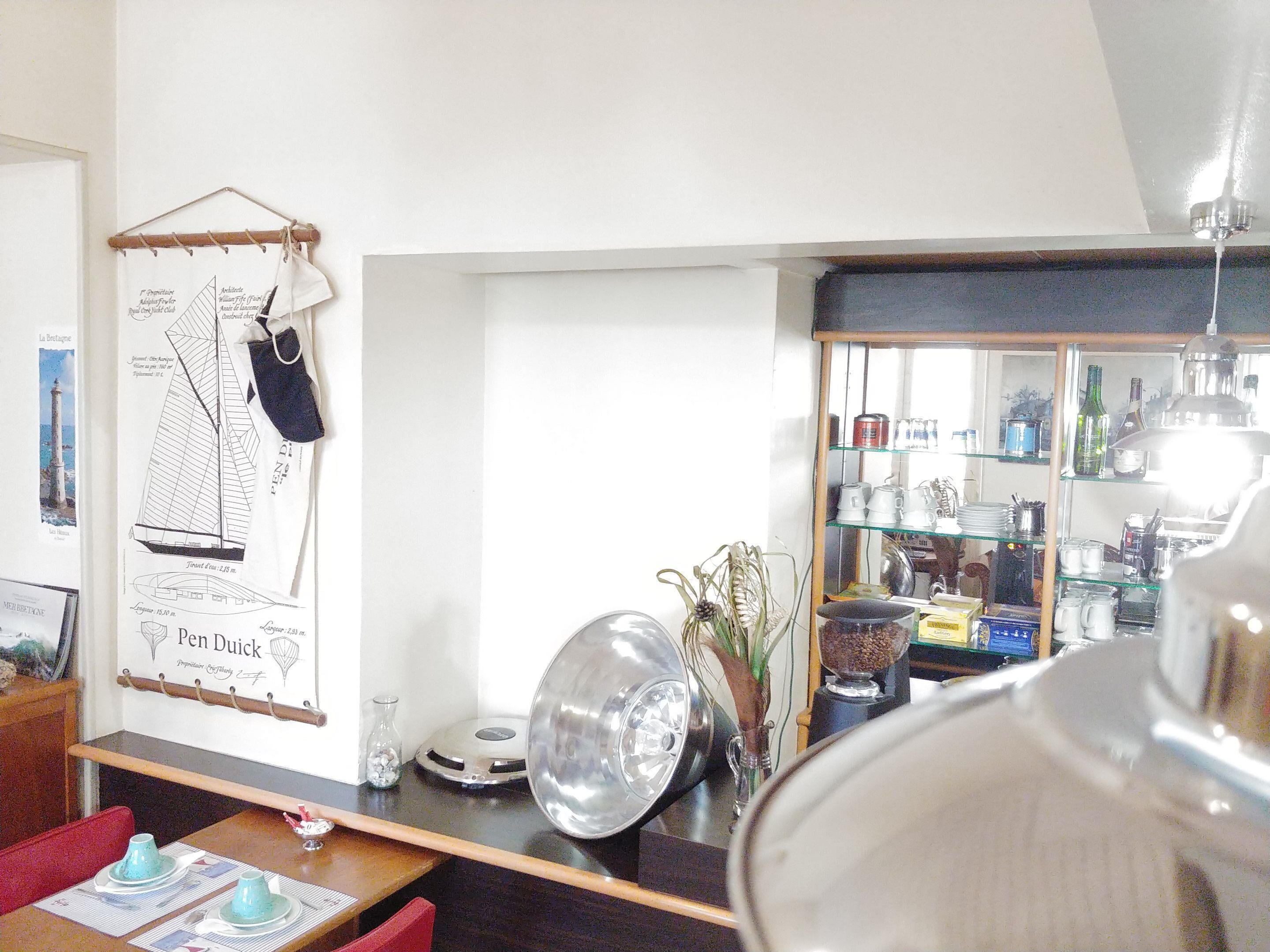 Una habitación con comedor, un mapa colgado en la pared y una zona de cocina con estantes de vidrio.