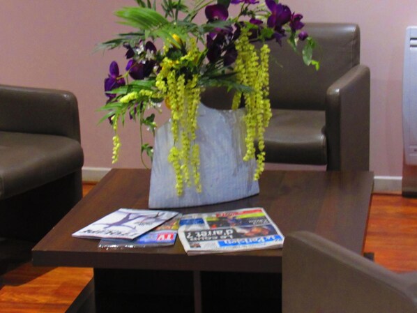 A table with a vase of flowers and magazines. - Hotel Gallieni (Gennevilliers)