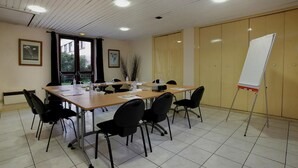A conference room with a long table, black chairs, a whiteboard, and a window with curtains. - Hotel Gallieni (Gennevilliers)