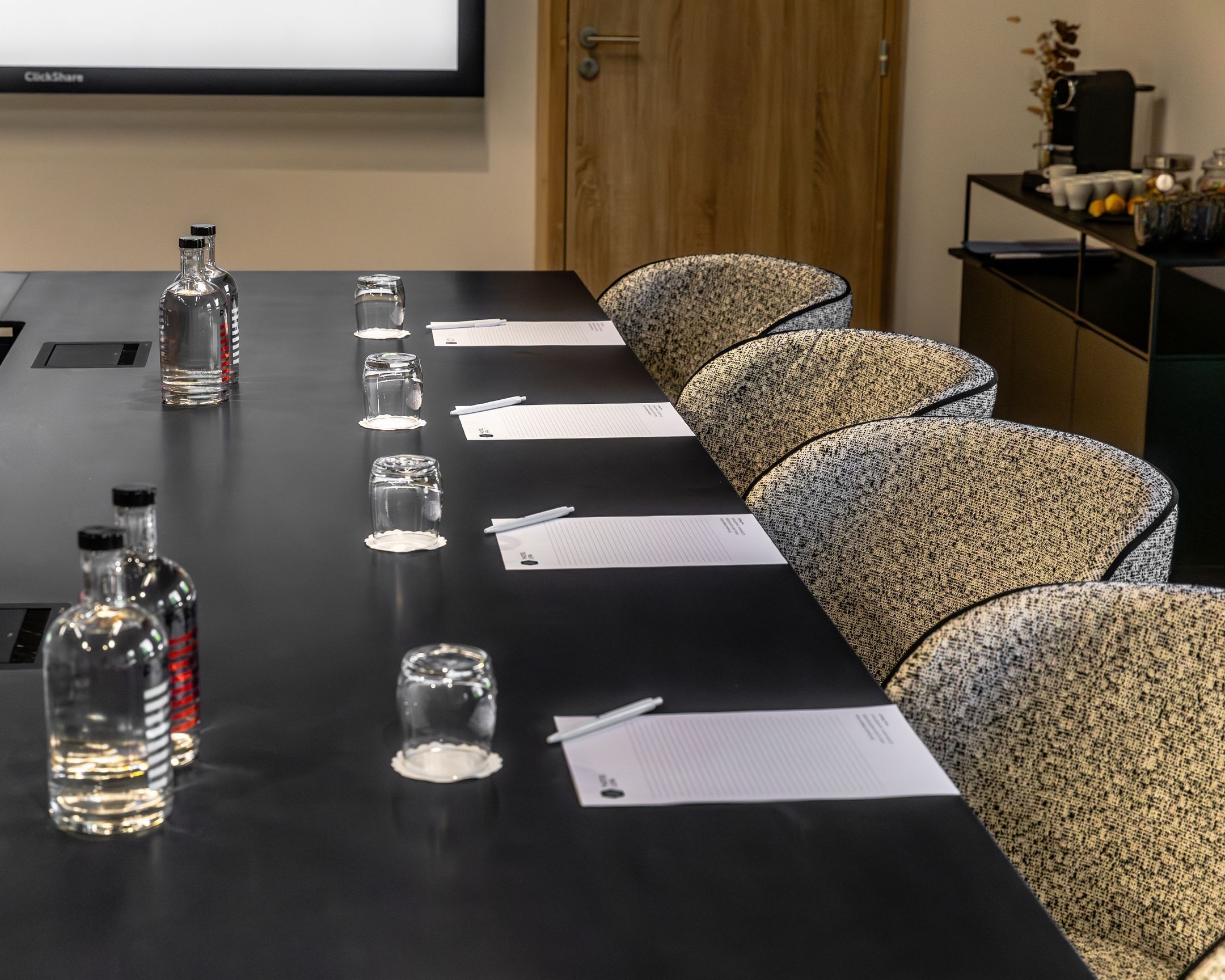 A conference table with documents, pens, and glassware.