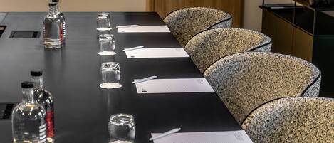 A conference table with documents, pens, and glassware.