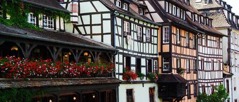 A traditional half-timbered building with multiple stories, balconies with red flowers, and a steeply pitched roof.