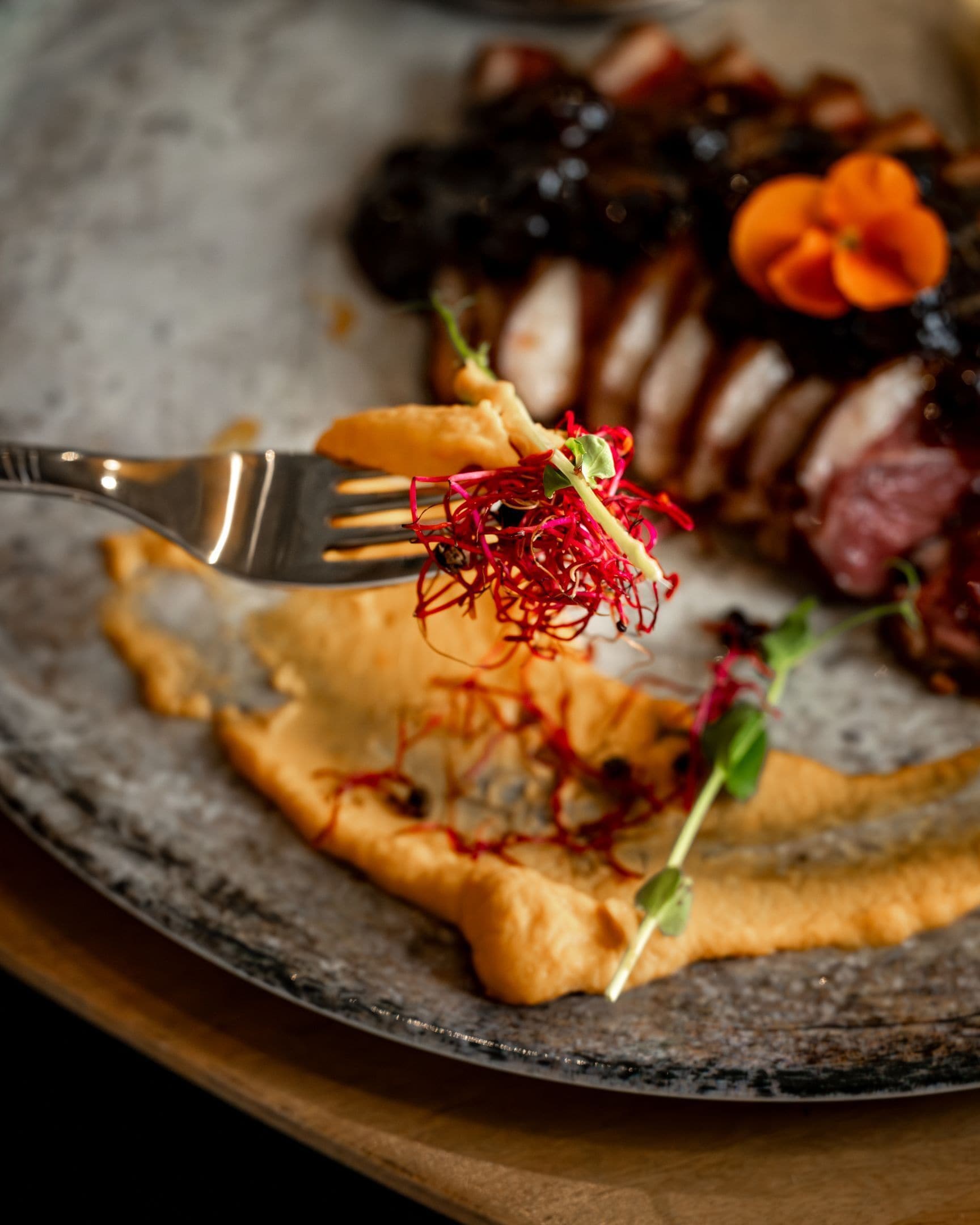 A plate with various food items, including a piece of meat, some vegetables, and a fork.