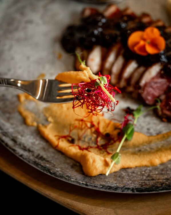 Un plato con diferentes alimentos, incluyendo un trozo de carne, verduras y un tenedor.