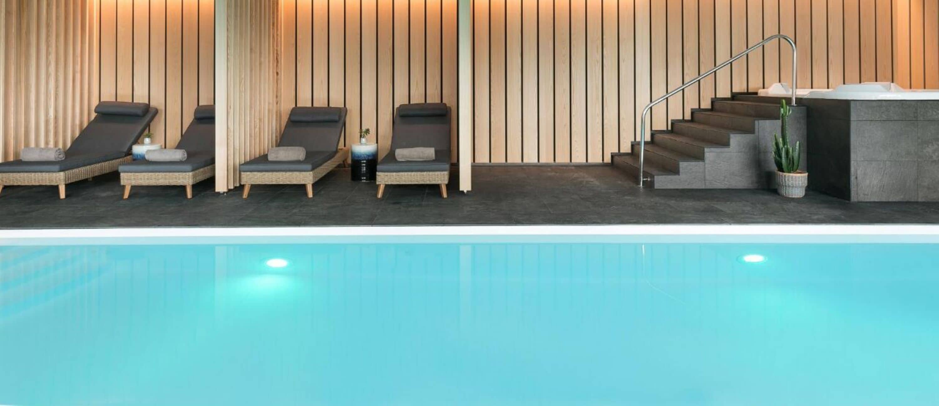 Zona de piscina con sillones de descanso y una escalera que conduce a un nivel superior.
