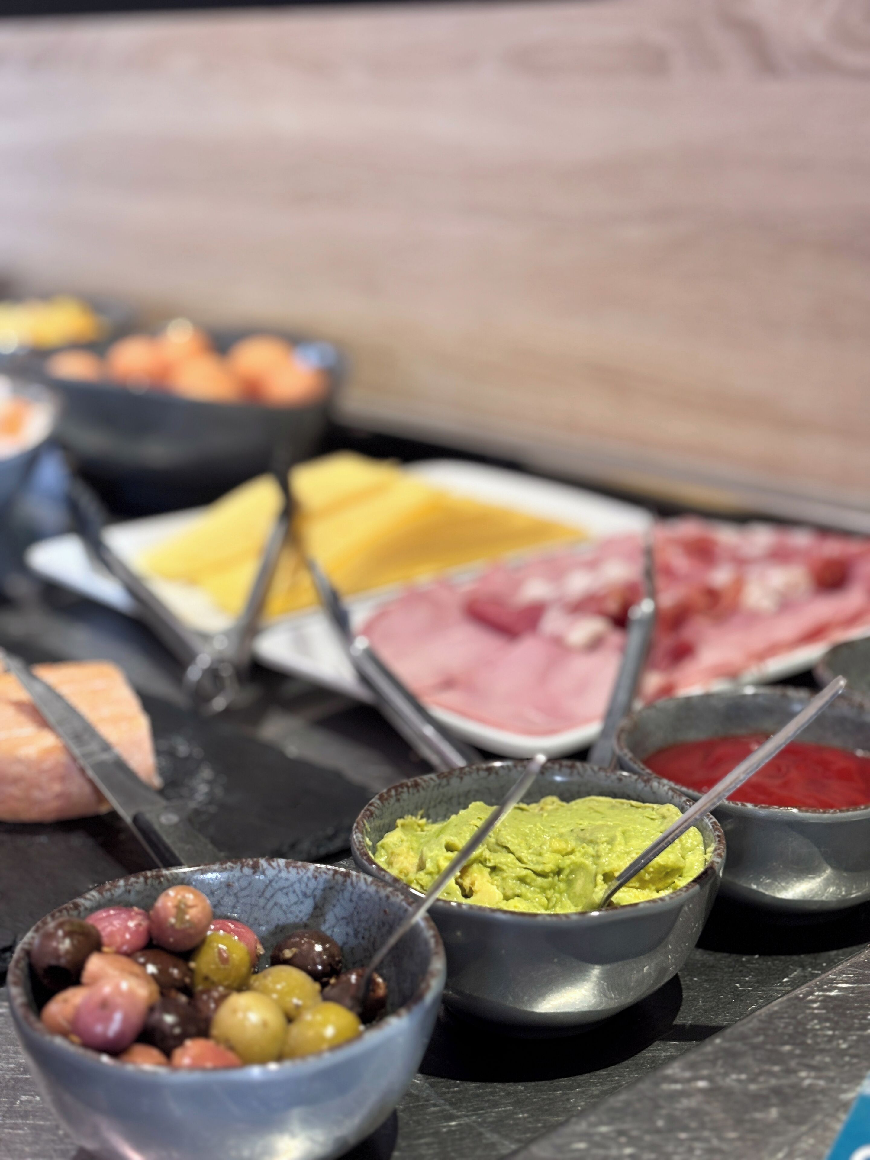 A buffet with various food items including meats, cheeses, and olives.