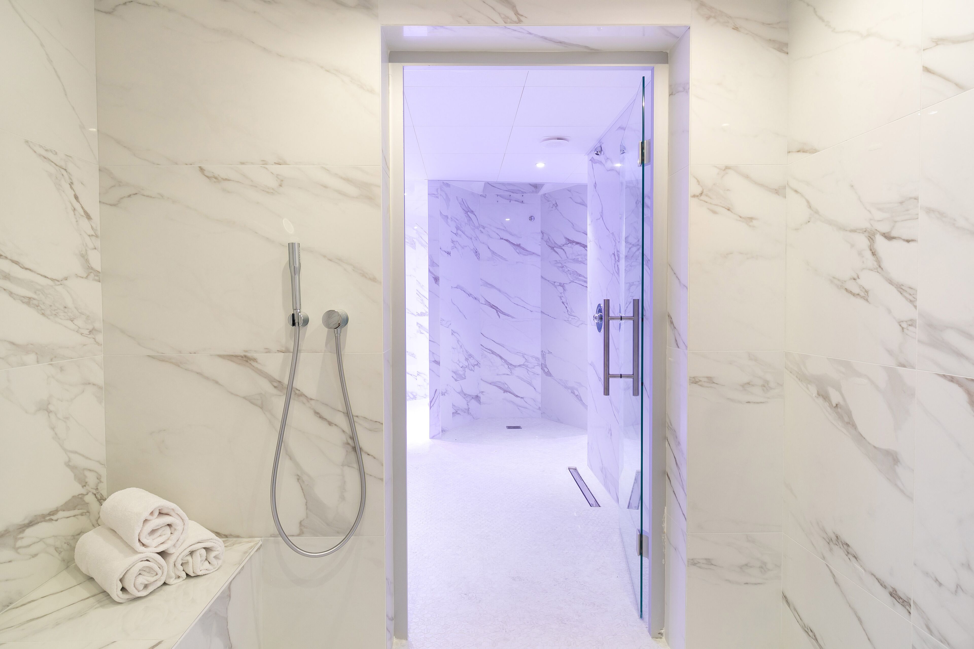 A bathroom with marble walls and a shower area.