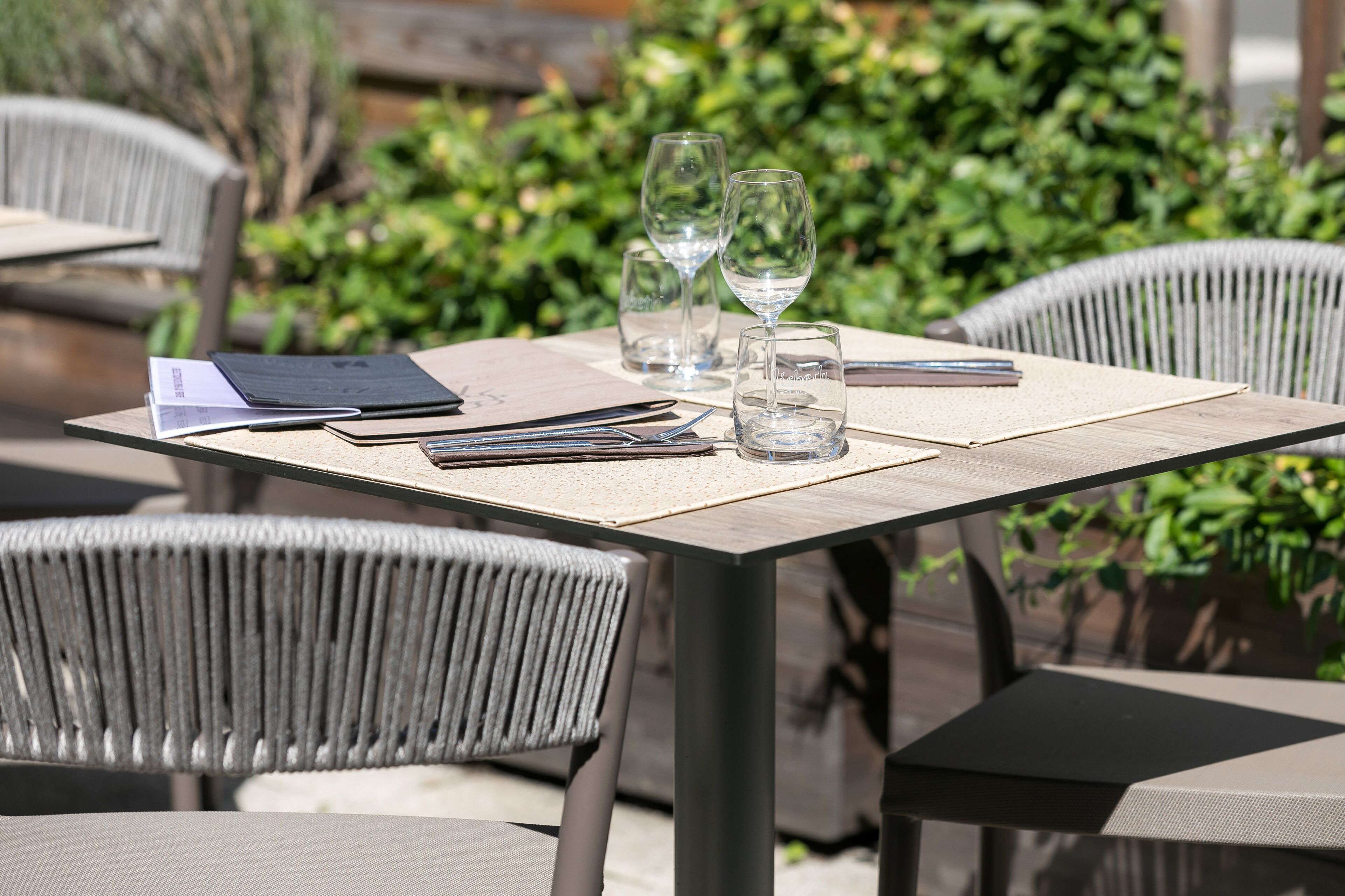 A table set outdoors with a menu, glasses, and a notebook.