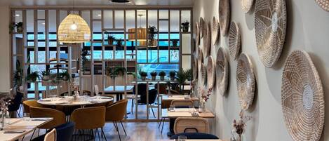 A modern restaurant interior with wooden flooring, round tables, and chairs.