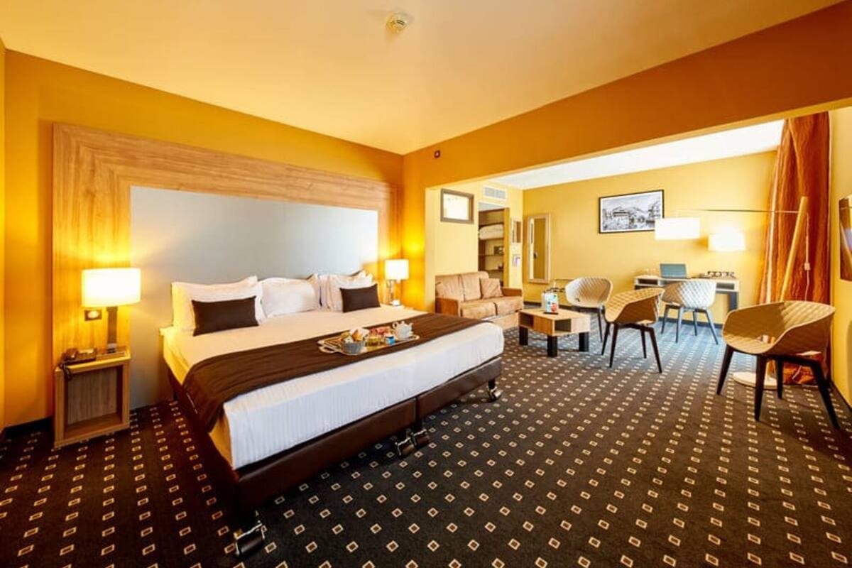 A hotel room with a large bed, bedside tables, a desk, and a chair.