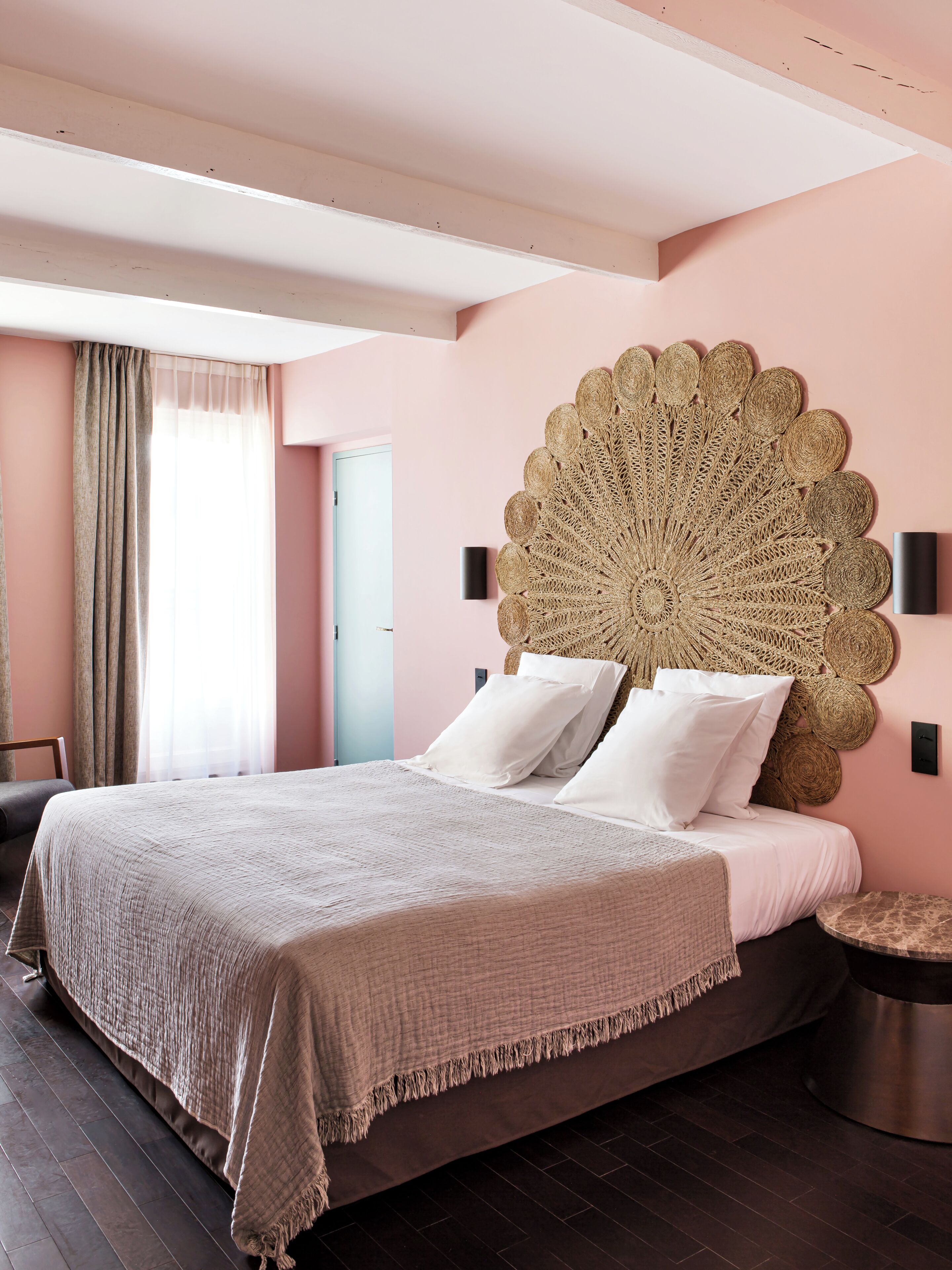 A bedroom with a large bed, a decorative wall headboard, a bedside table, and a view of a door.