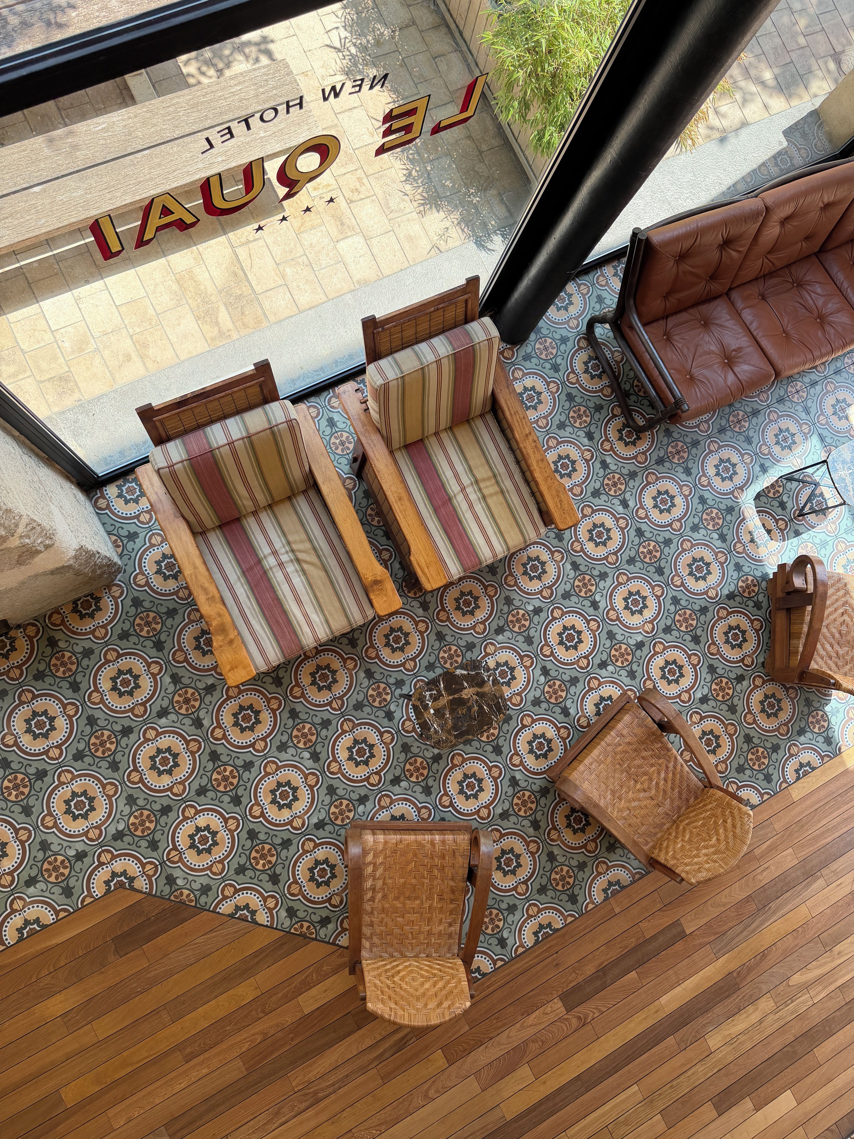 Una habitación con piso estampado, dos sillones a rayas, un sofá marrón y una silla de madera.