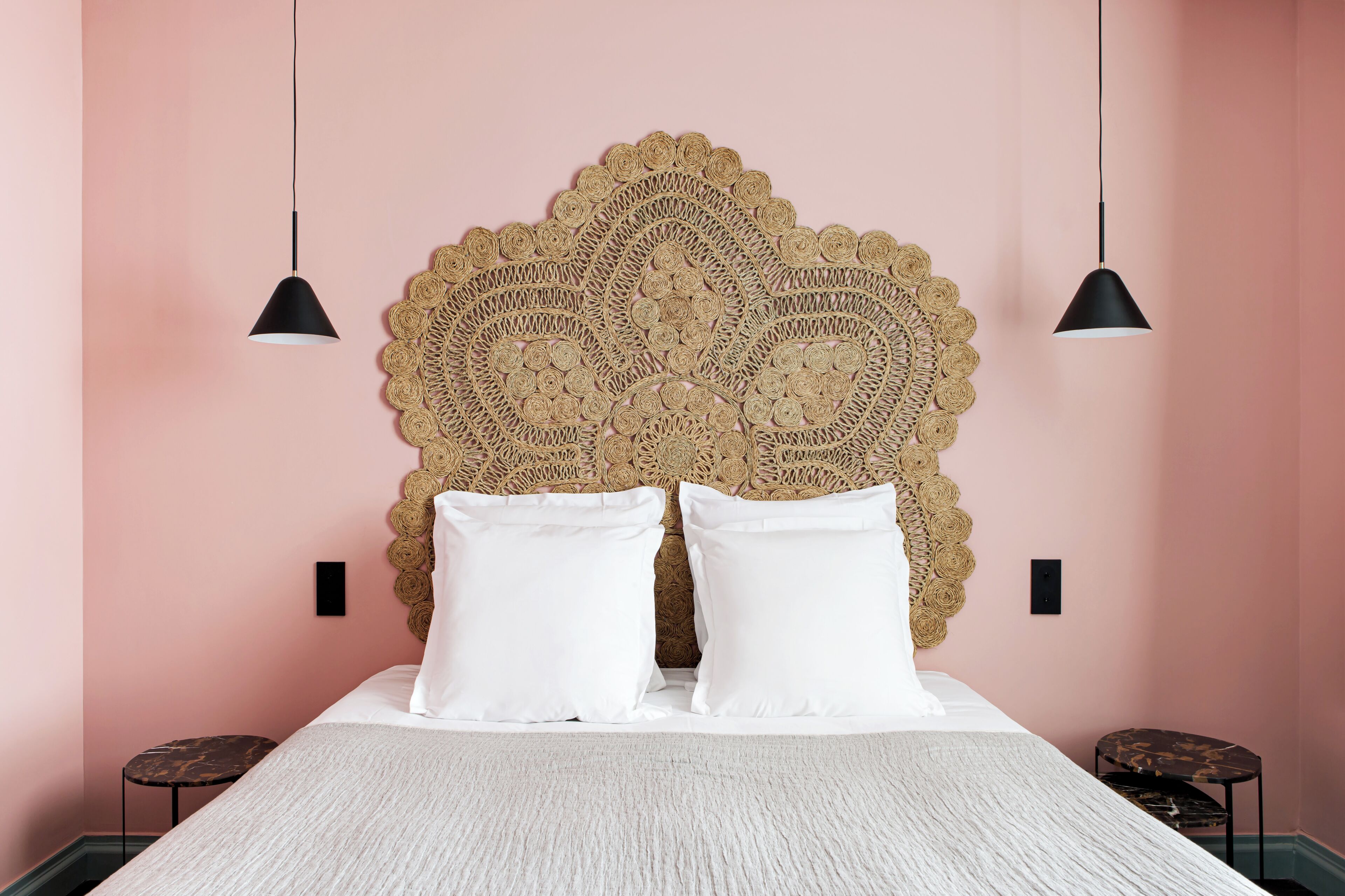 A bed with a textured headboard, two bedside lamps, and a textured rug.