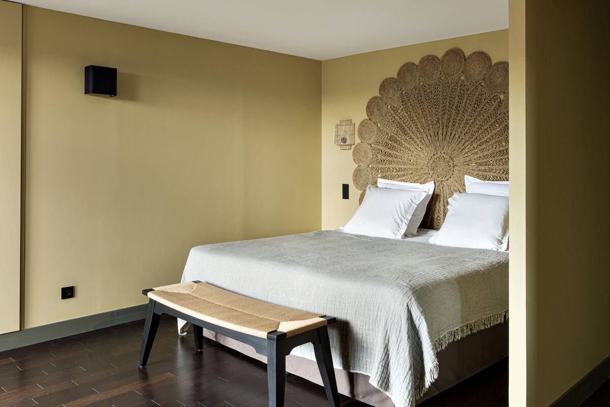 A neatly arranged bedroom with a bed, a bench, and a decorative wall piece.