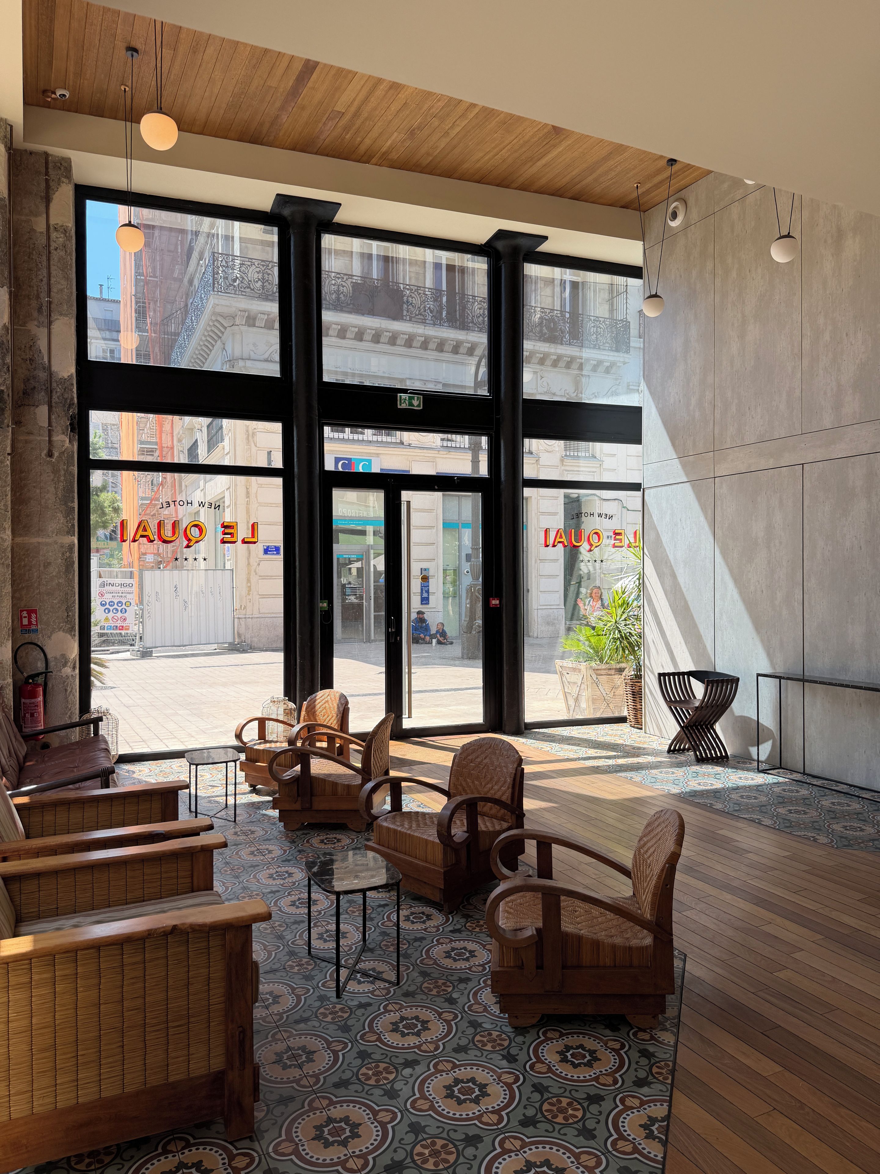 A modern interior with large windows, wooden flooring, and a seating area with chairs and a sofa.