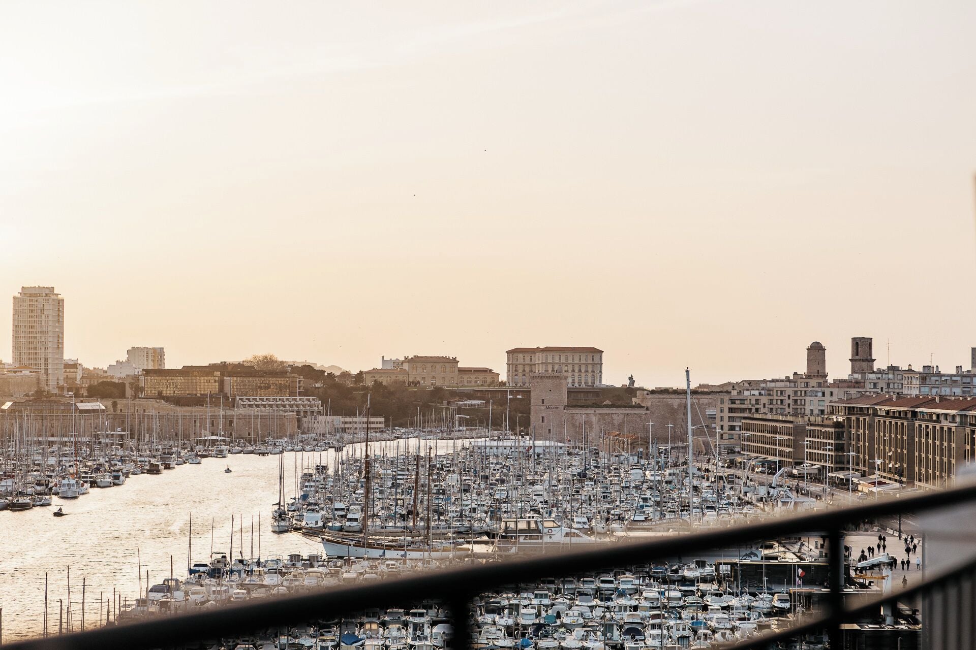 Un port de plaisance rempli de nombreux bateaux, un paysage urbain avec différents bâtiments et un ciel dégagé.